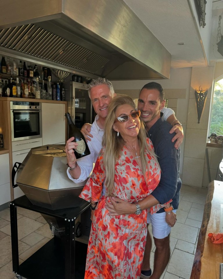 two men and a woman are posing for a picture in a kitchen