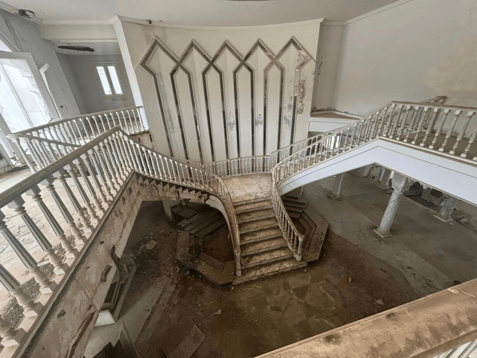 a spiral staircase in an abandoned building with a white railing