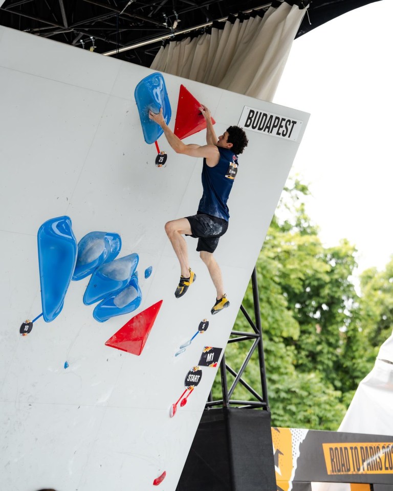 a man climbing a wall with a sign that says ' budapest ' on it