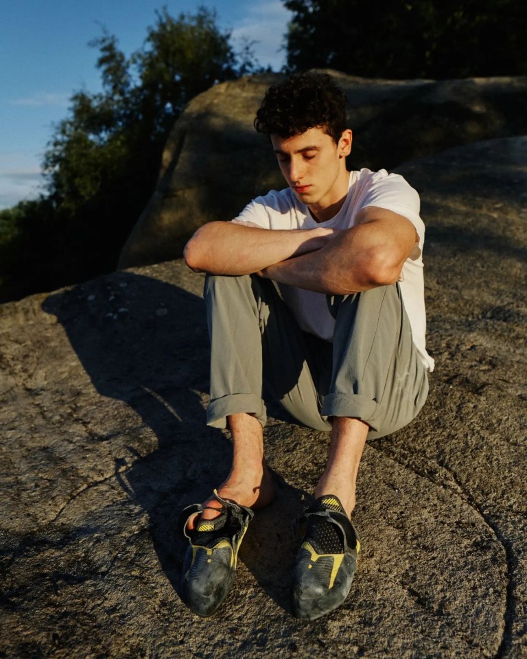 a man sits on a rock with his head down