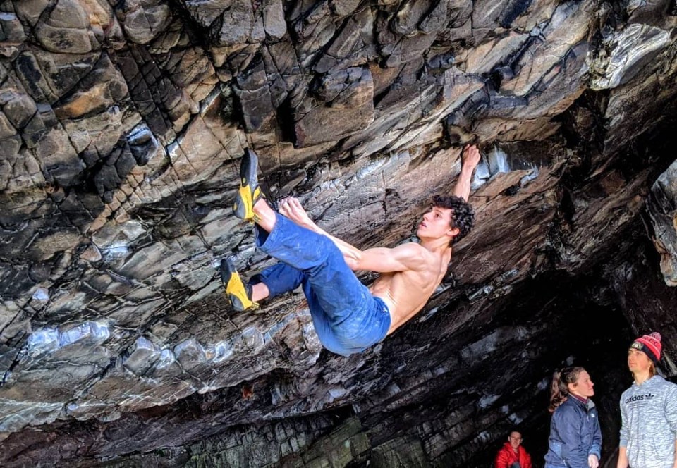 a man climbs a rock wall while a group of people watch