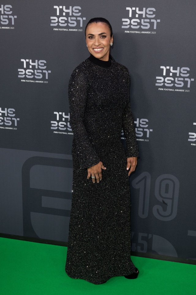 a woman in a black dress stands in front of a wall that says the best