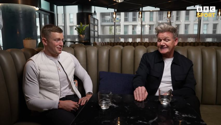 two men sit at a table with bbc sports written on the bottom