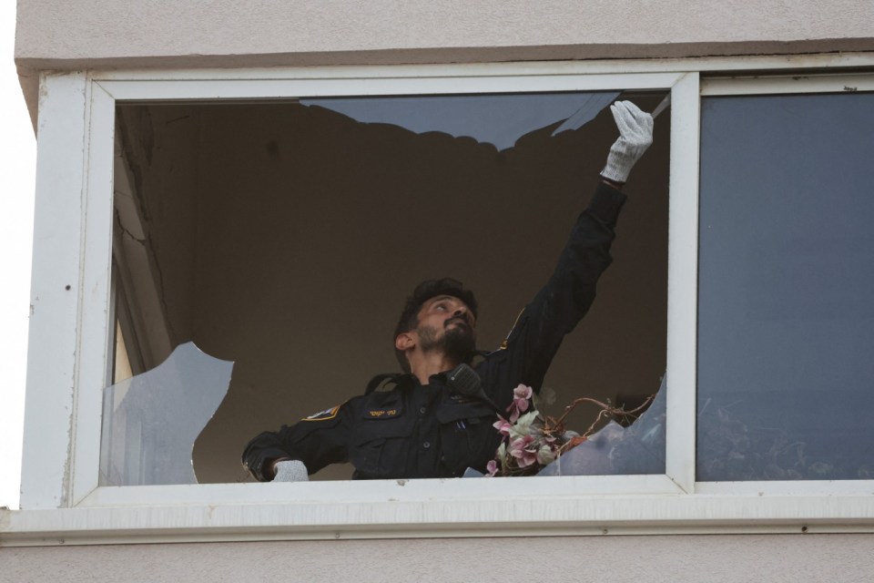 A cop inspects a smashed window at the site of the explosion