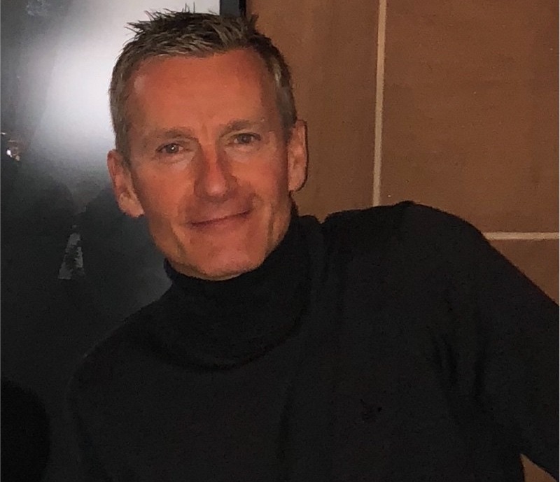 a man wearing a black turtleneck is smiling for the camera