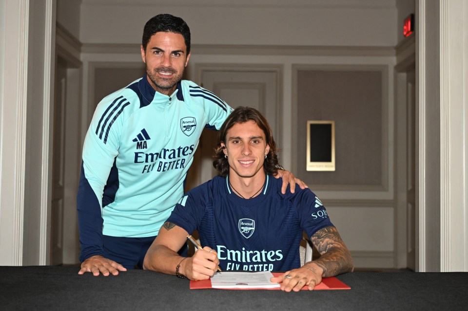 a man wearing an emirates fly better shirt stands next to another man