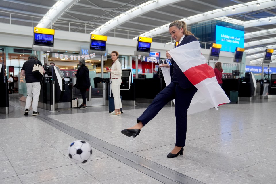 a woman kicking a soccer ball while holding an english flag