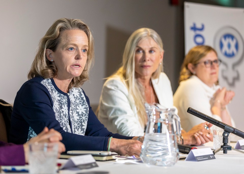 three women sit at a table in front of a sign that says ot