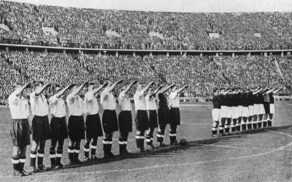 a black and white photo of a soccer team saluting