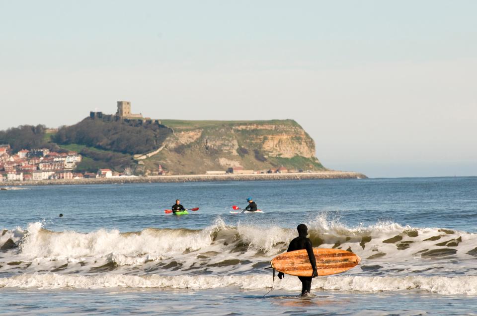 Scarborough Castle overlooks the beaches where people kayak and surf