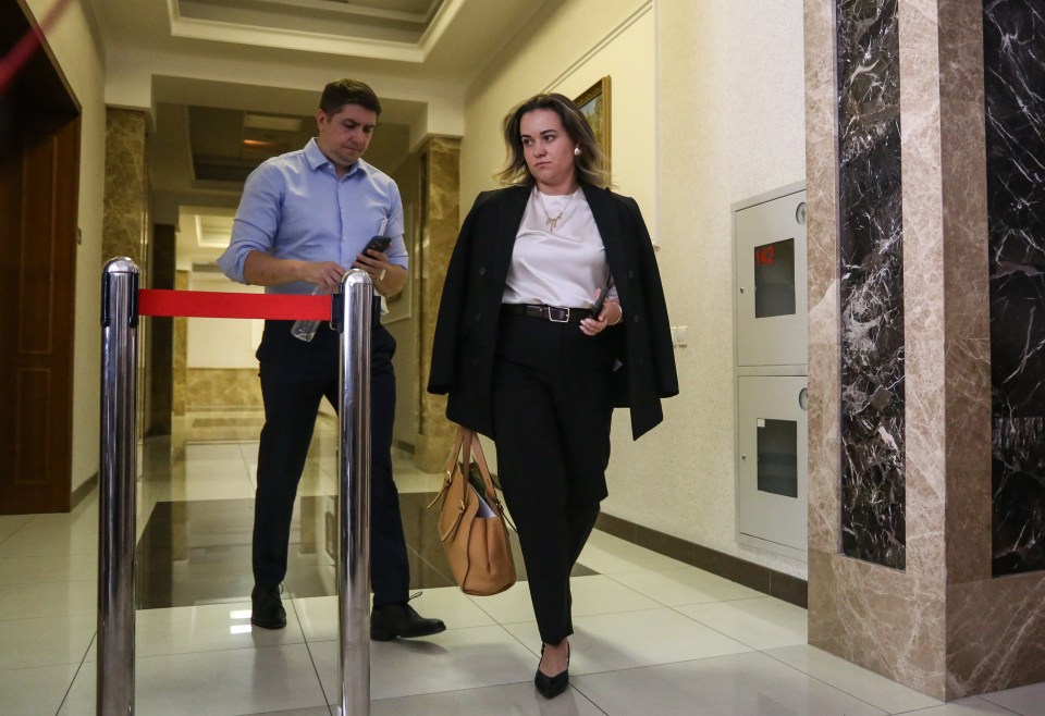 a woman walking down a hallway with a man standing behind her