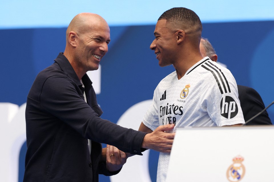 two men shaking hands with one wearing an emirates shirt