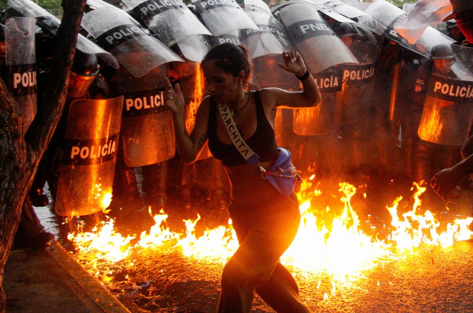 A demonstrator reacts when Molotov cocktails hit the ground in front of cops