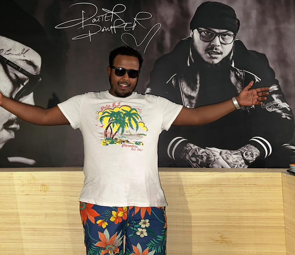 a man wearing a white shirt that says paradise on the beach