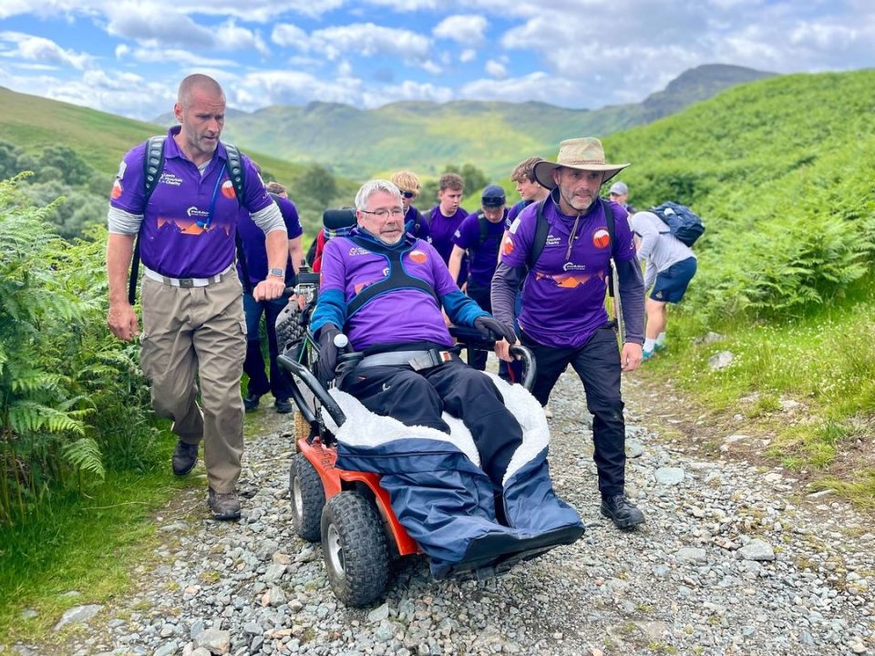 Flatt and his supporters have to overcome rocky paths, water, and mud to get him and the 200kg wheelchair up the mountains