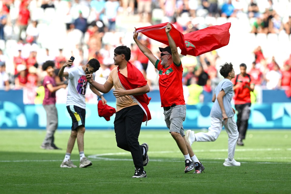 a group of people running on a soccer field holding flags