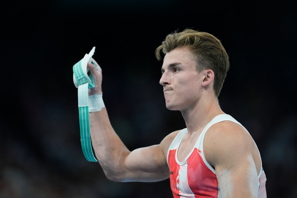 a young man in a red and white tank top holds a ribbon in his hand