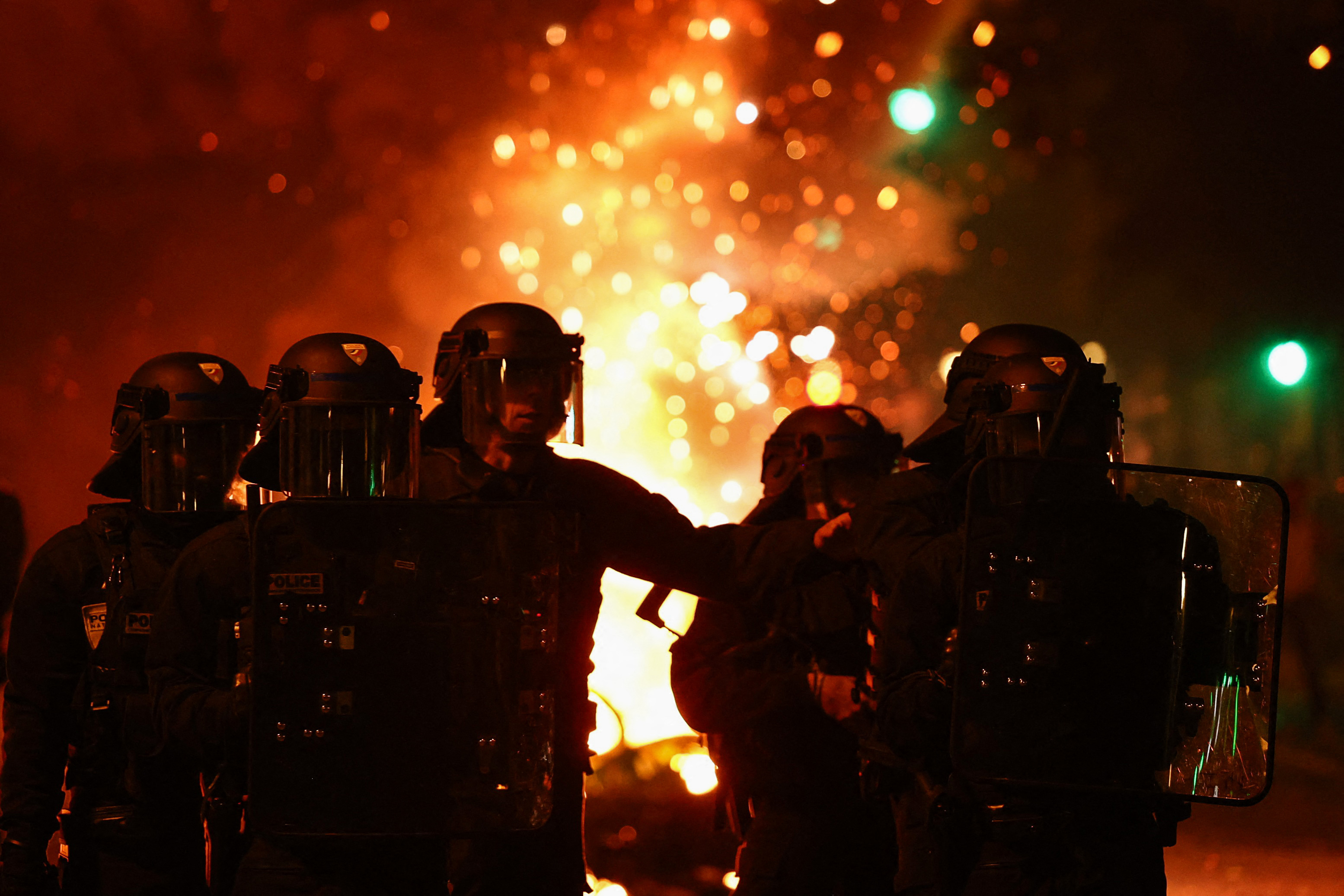 French riot police stand in position near burning bicycles