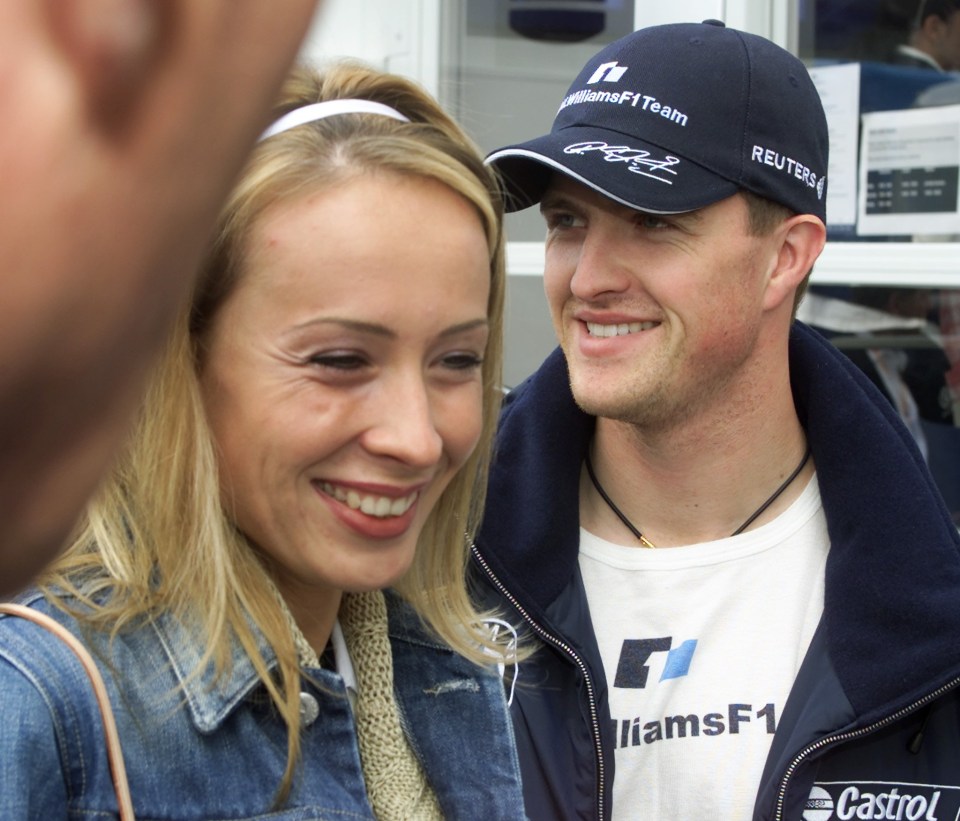 a man wearing a williams f1 team hat smiles next to a woman