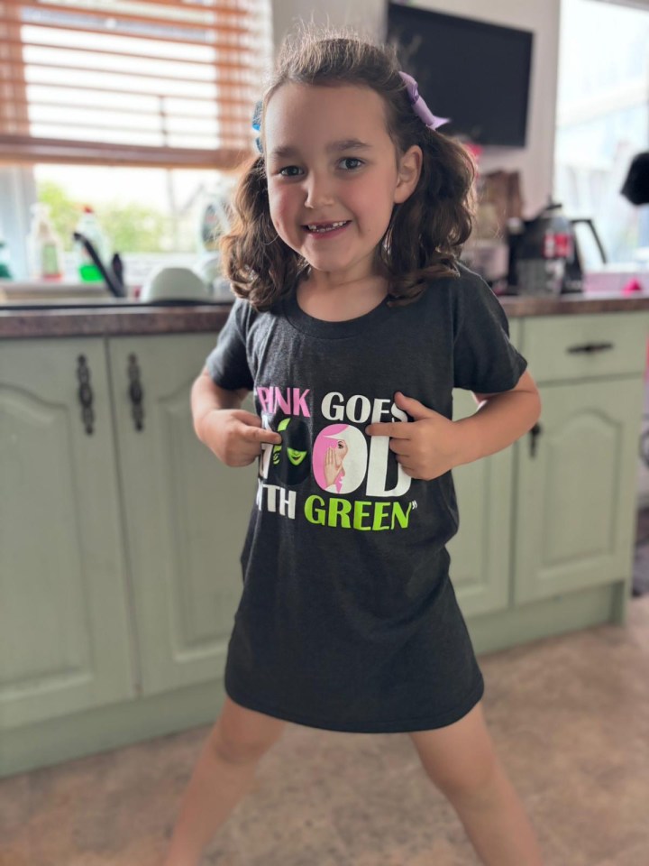 a little girl wearing a black shirt that says " pink goes 4th green "