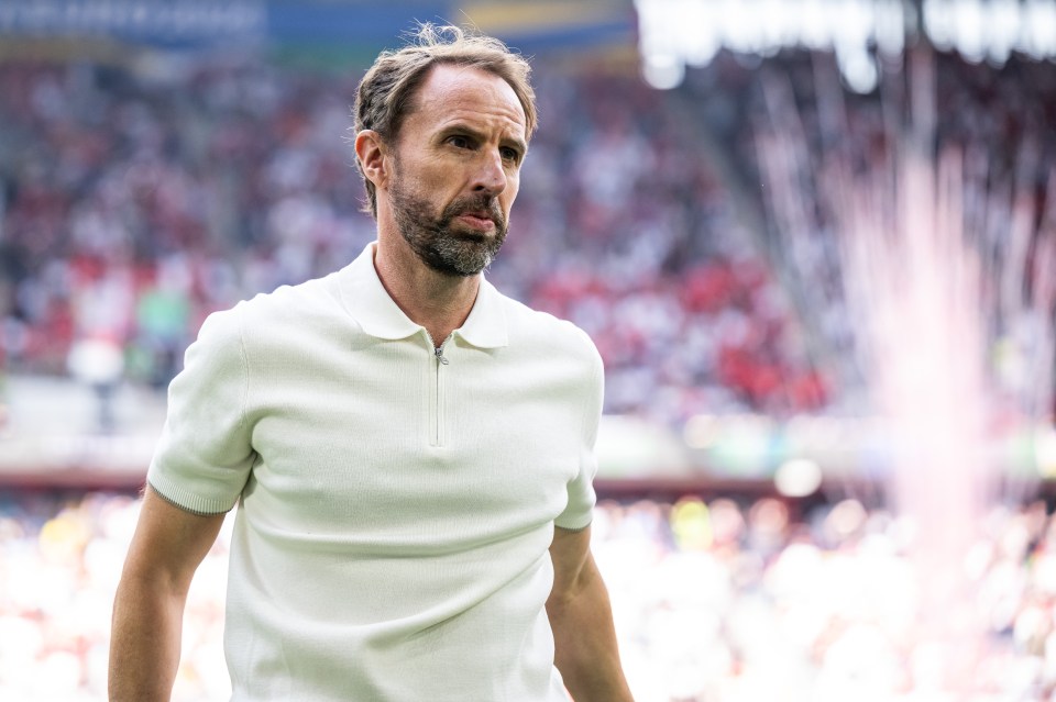 a man in a white polo shirt stands on a soccer field