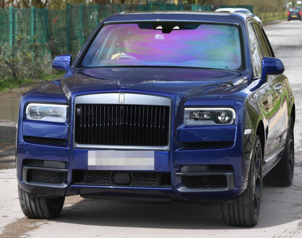 a blue rolls royce is parked on the side of the road