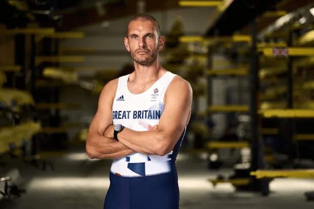 a man in a great britain tank top stands with his arms crossed