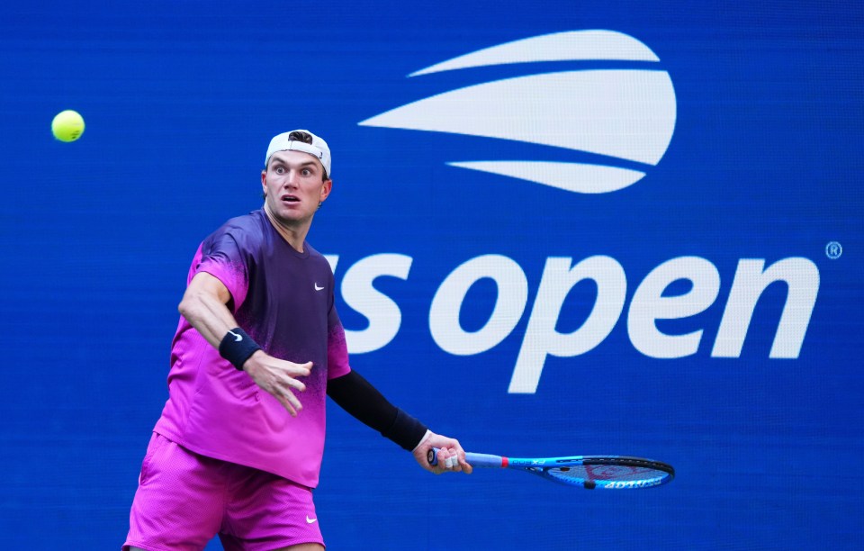 a man playing tennis in front of a us open logo