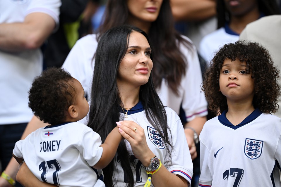 a woman holds a baby wearing a jersey that says jones