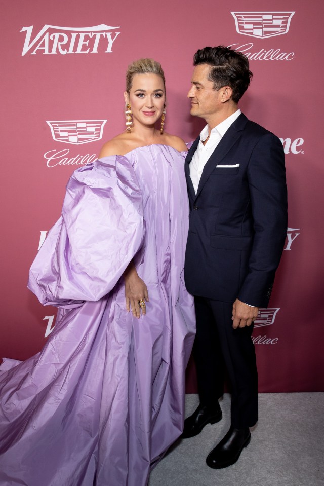 a woman in a purple dress stands next to a man in a suit