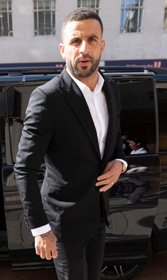 a man in a suit stands in front of a black van