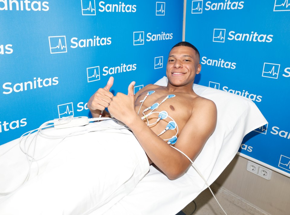 a shirtless man is giving a thumbs up in front of a wall that says sanitas