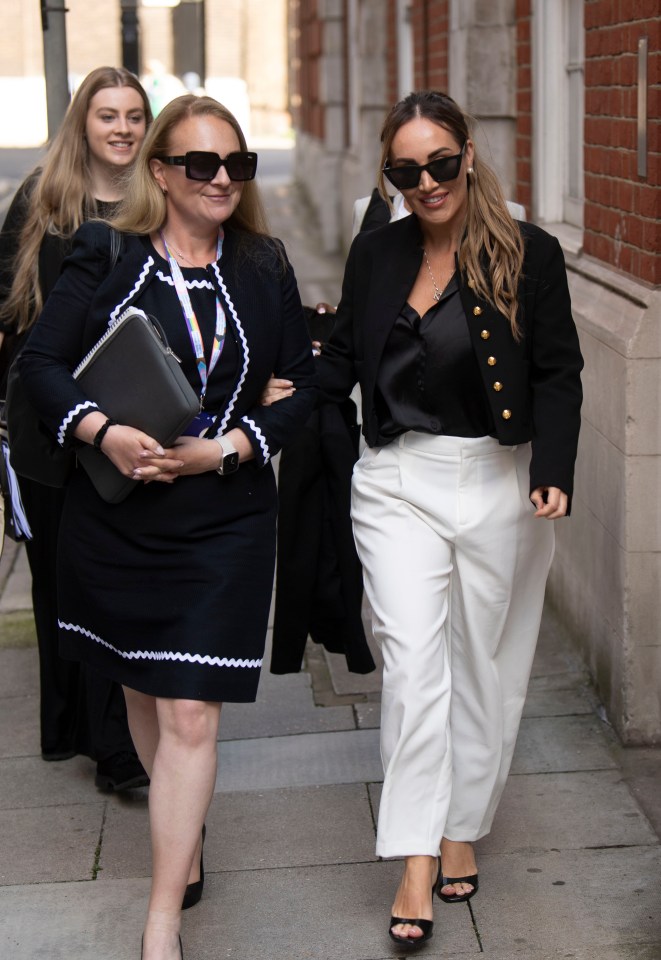 two women walking down a sidewalk with one wearing sunglasses