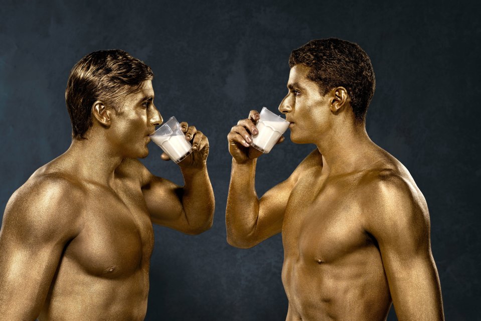 Beach volleyball players Javier and Joaquin Bello pose face to face, each raising a glass.