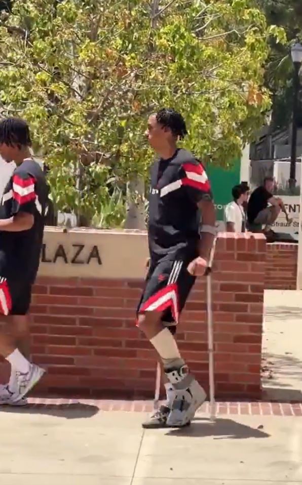 a man with crutches is walking down a sidewalk next to a brick wall .