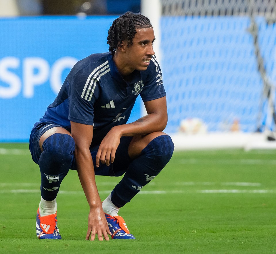 a soccer player is squatting down in front of a blue sign that says spc