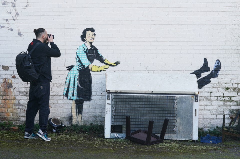 a man taking a picture of a painting on a wall