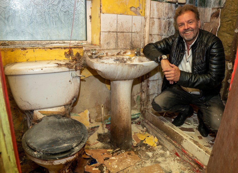 a man kneeling in a bathroom next to a toilet and sink