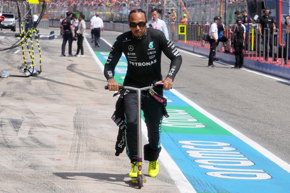 Lewis Hamilton arrives at the race track on a scooter so no one can stop him, and he’s wearing ear buds so he can pretend he can’t hear the fans’ demands for a selfie