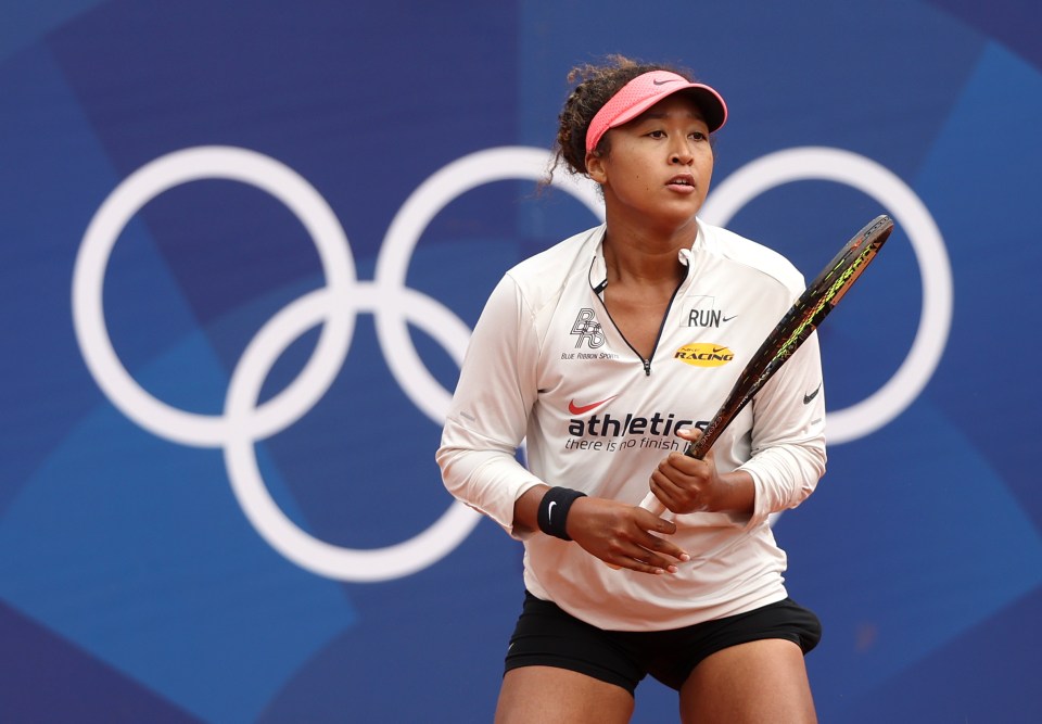 a woman holding a tennis racquet wearing an athletics shirt