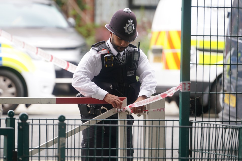 A police officer attaches tape at the scene