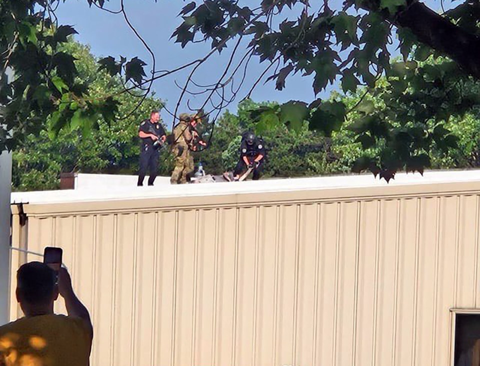 Police surround the body of the shooter on a roof nearby