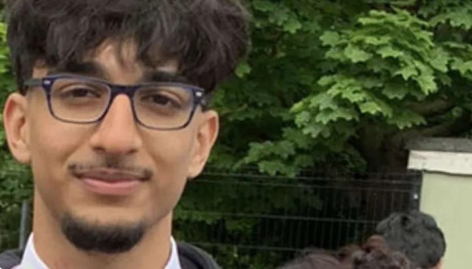 a young man with glasses and a beard is smiling for the camera .