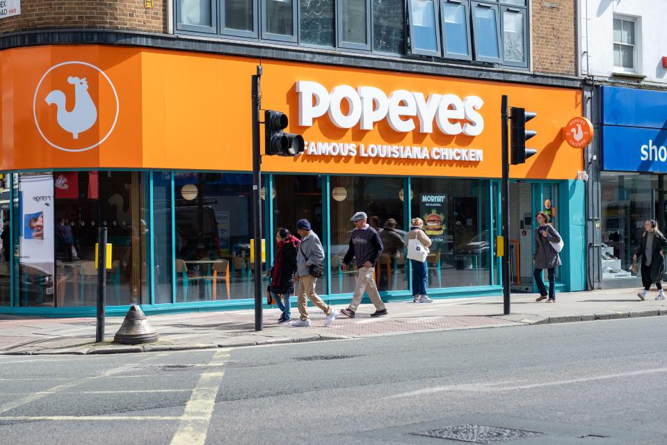 people walking in front of a popeye 's famous louisiana chicken restaurant