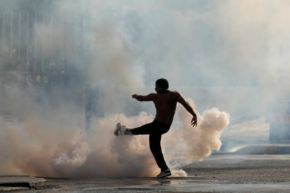 A protester kicks a tear gas canister fired by police