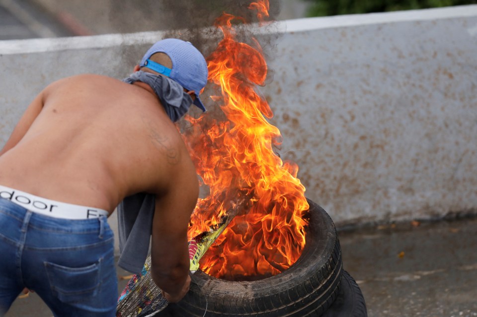 A protester sets a tyre on fire