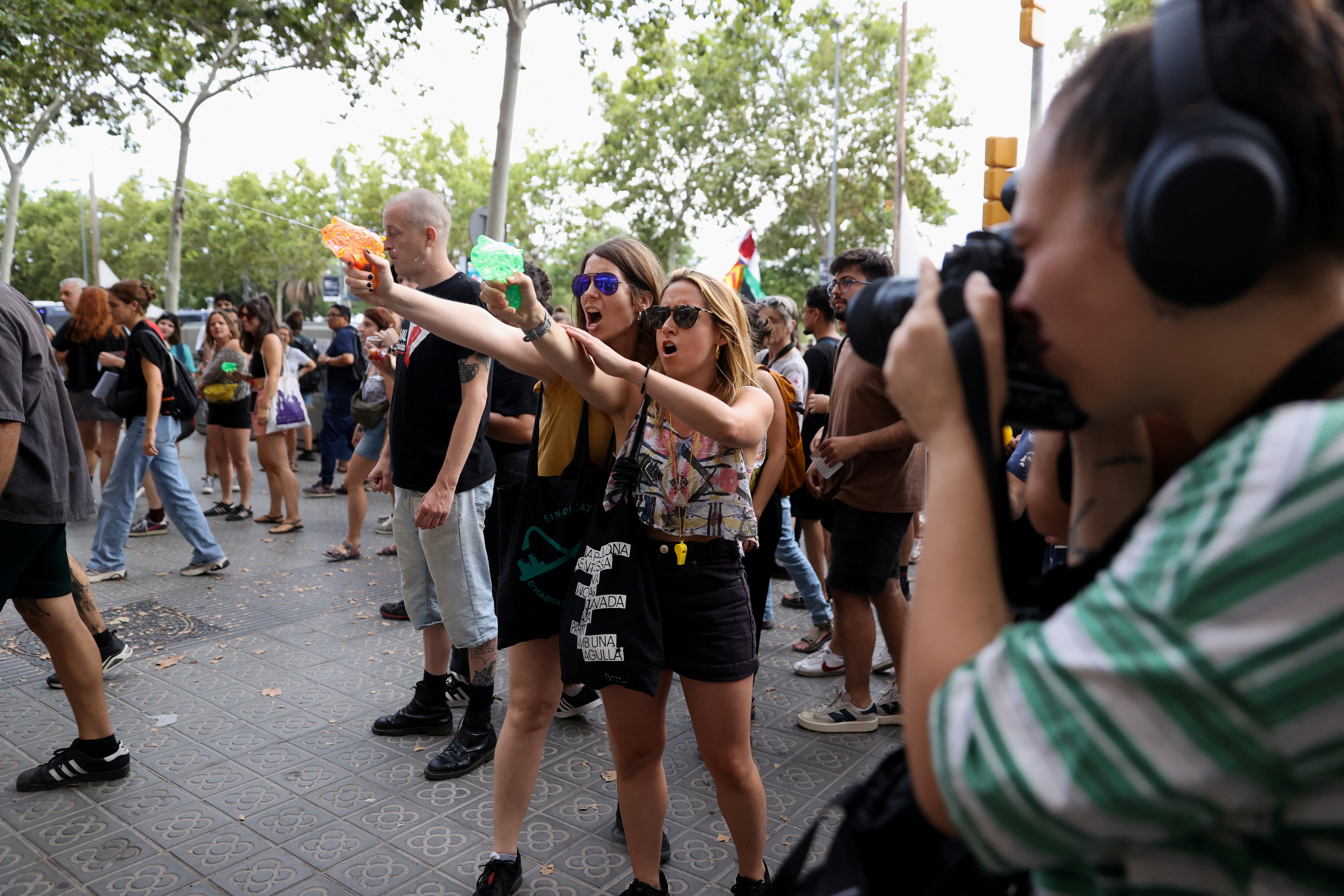 Two women can be seen pointing their water pistols, attempting to soak tourists in Barcelona