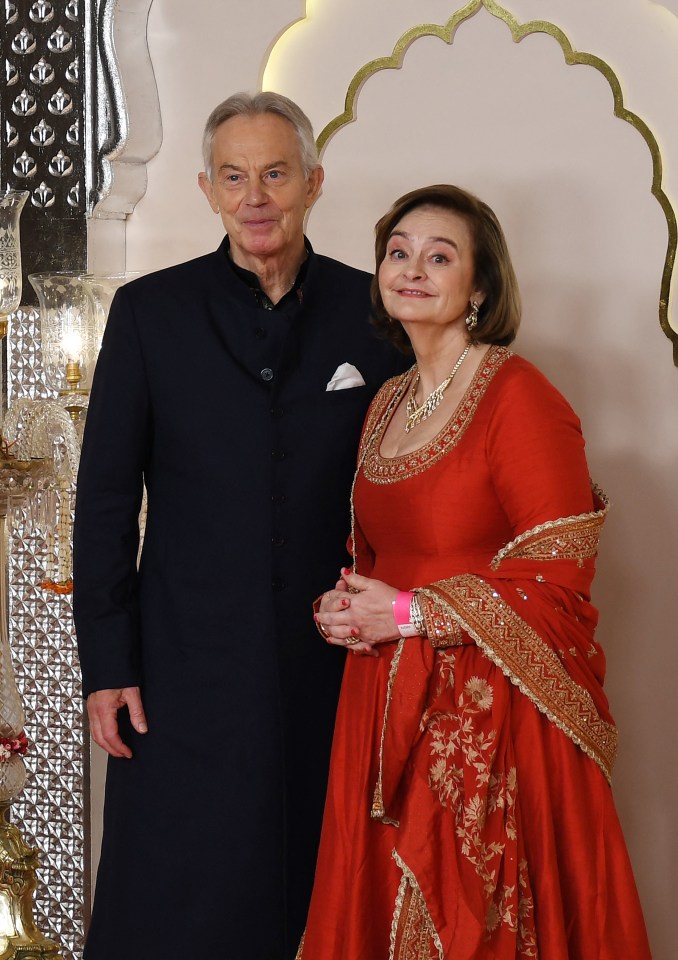 a woman in a red dress stands next to a man in a black coat