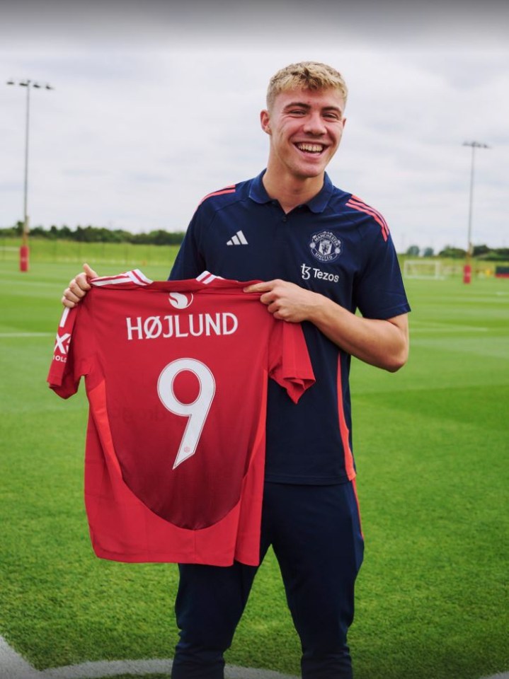 a man holding up a red jersey with the number 9 on it