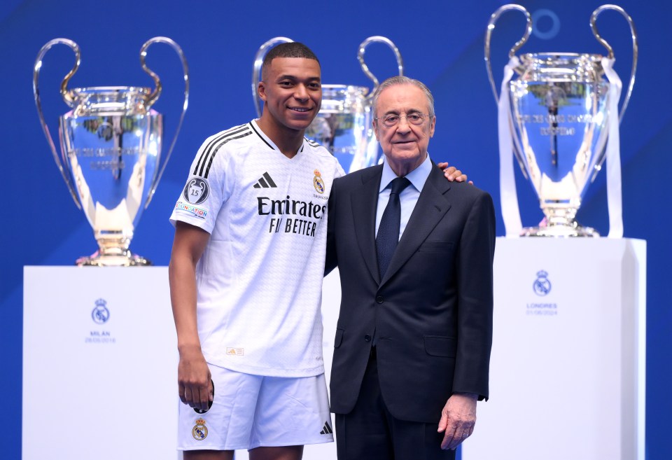 a man in a suit stands next to a soccer player wearing an emirates fly better jersey